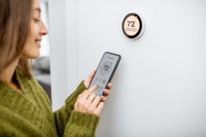 woman-adjusting-thermostat-using-her-smartphone