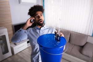 distressed-person-with-phone-catching-water-in-a-bucket
