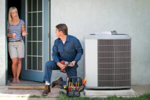 HVAC-technician-repairing-an-AC-unit-while-talking-to-a-homeowner